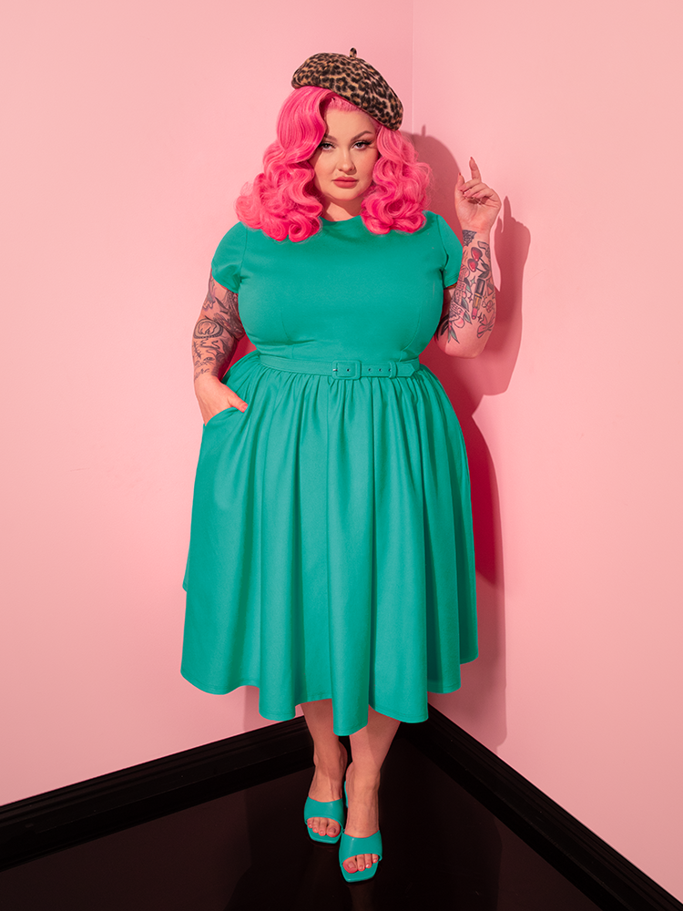 With poise and charm, the female model presents the Avon Swing Dress in Aquamarine by Vixen Clothing, showcasing its timeless allure in a variety of poses.
