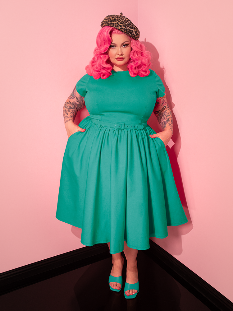 The stunning female model effortlessly transitions through poses while showcasing the Avon Swing Dress in Aquamarine from the retro fashion label Vixen Clothing.