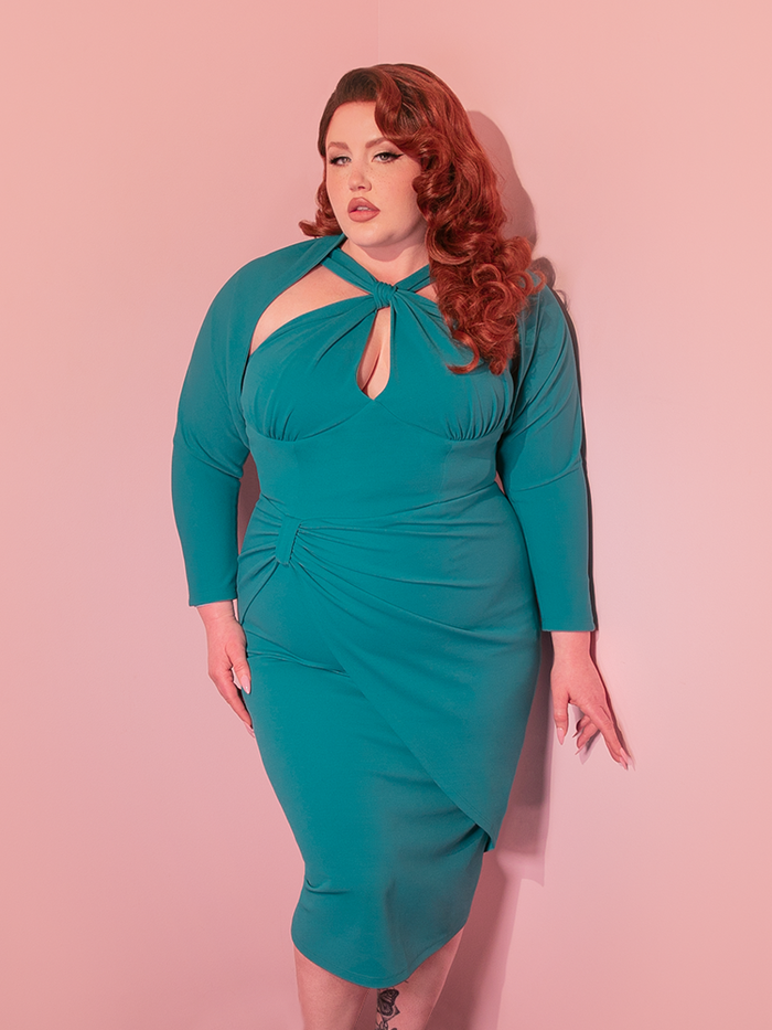 The moment she slips into the Golden Era Wiggle Dress in Aqua, complete with its chic matching bolero, she's instantly transported to a time where elegance and grace reigned supreme, showcasing her love for vintage dresses with every step.