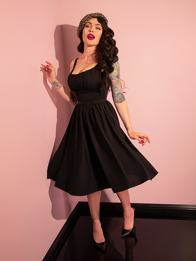 Radiating elegance, Micheline Pitt captivates attention in the retro-inspired Ingenue Dress in Black from Vixen Clothing, showcasing its allure through various poses.