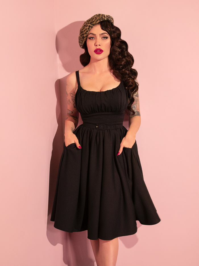 Micheline Pitt effortlessly transitions through poses while showcasing the retro-inspired Ingenue Dress in Black from Vixen Clothing.
