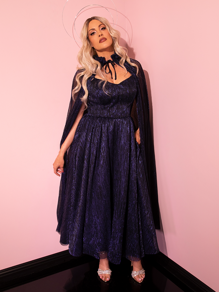 In a glamorous display, a captivating model models the LABYRINTH™ Jareth Gown With Matching Cape from Vixen Clothing's retro line.