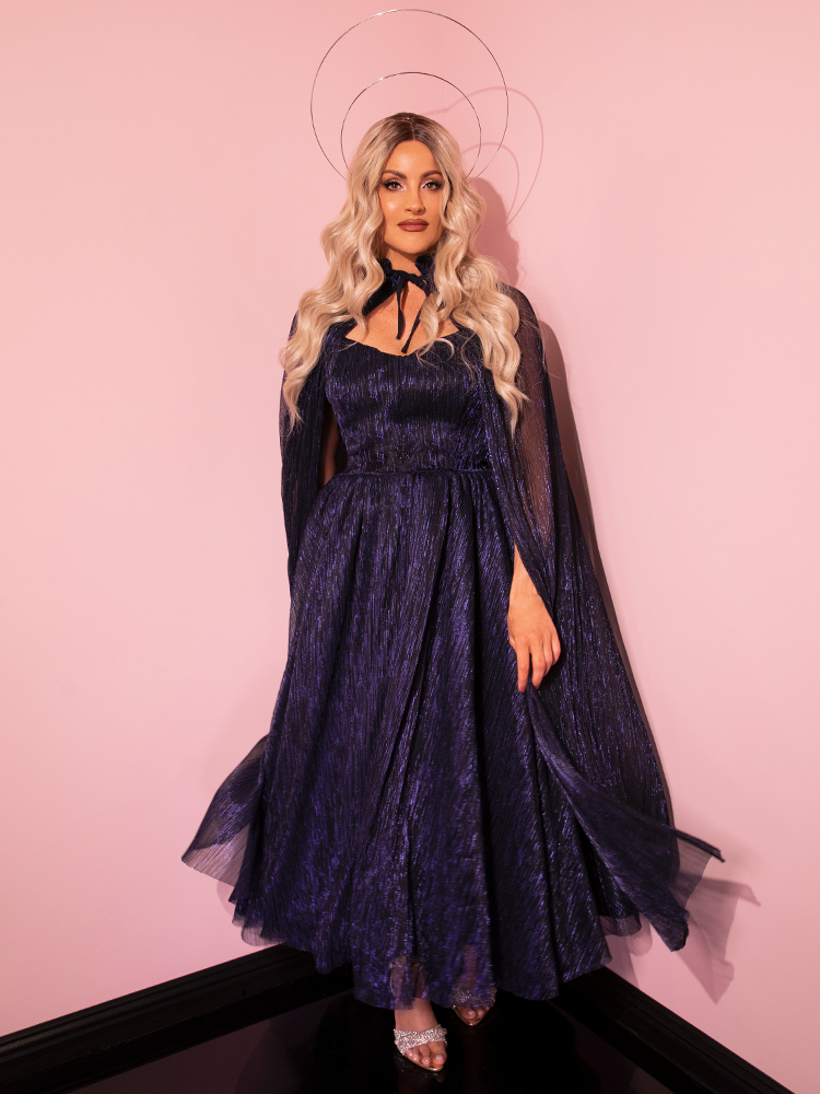 With a touch of timeless elegance, the LABYRINTH™ Jareth Gown With Matching Cape in Midnight Blue by Vixen Clothing is beautifully adorned by this striking model.
