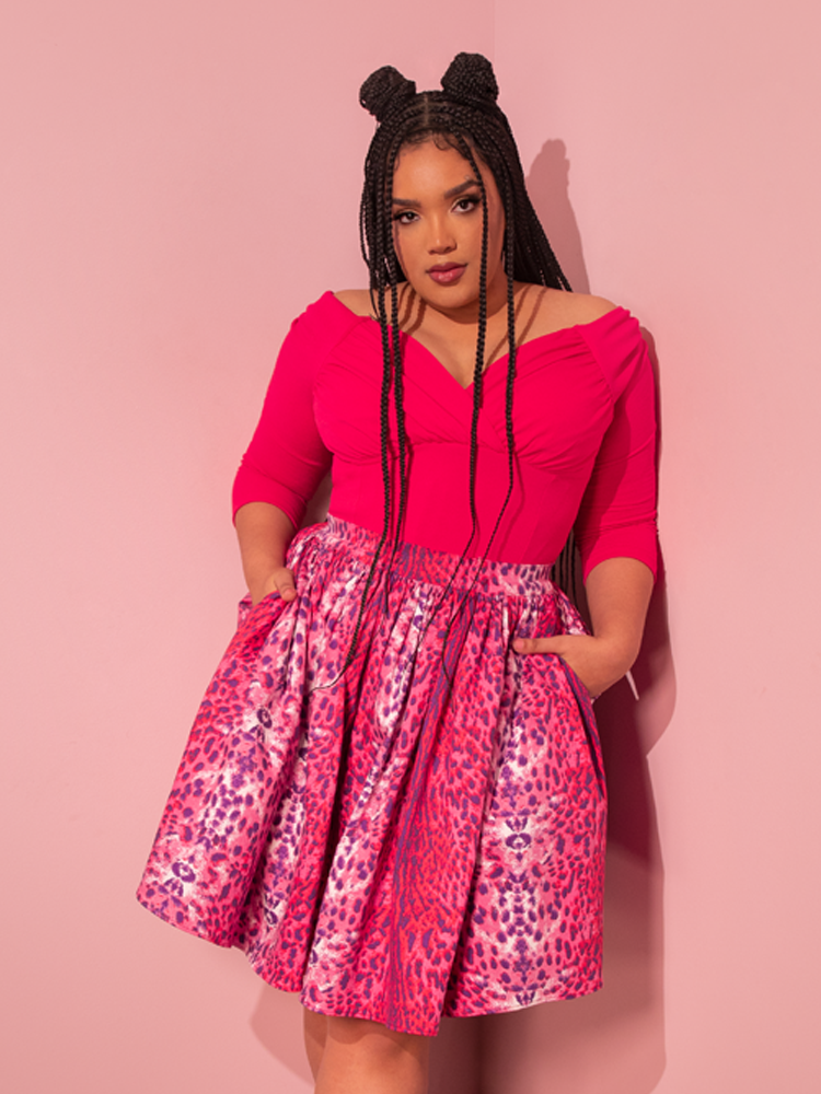 A stunning female model gracefully showcases a retro-inspired ensemble, accentuated by the vibrant Hot Pink Starlet Top from the renowned Vixen Clothing brand.