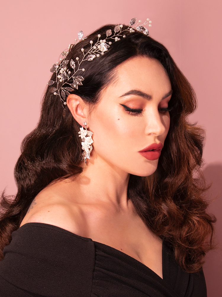 The retro charm of Vixen Clothing is embodied as an attractive brunette model playfully poses in the Vintage-Style Leaf and Pearl Hair Wire in Silver.
