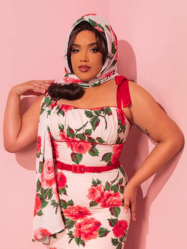 With an air of nostalgic charm, the stunning female model dons her retro-themed dress, featuring a delightful red rose print, and tastefully accessorizes it with Vixen Clothing's 1950s Inspired Chiffon Rose Scarf, paying homage to the bygone era of vintage glamour.