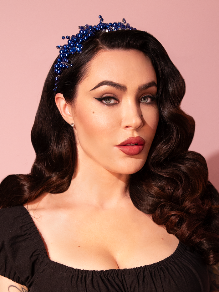 Micheline Pitt exudes timeless elegance as she graces the scene, showcasing the Rhinestone Beaded Headband in Royal Blue  from the retro clothing brand Vixen Clothing, adding a touch of vintage glamour to her impeccable style.
