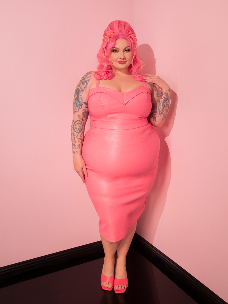 Transport yourself to the golden era as you admire the exquisite model donning the all new Bad Girl Maneater Top, crafted with love in Flamingo Pink Vegan Leather, a true gem from the retro dress and vintage clothing brand Vixen Clothing.