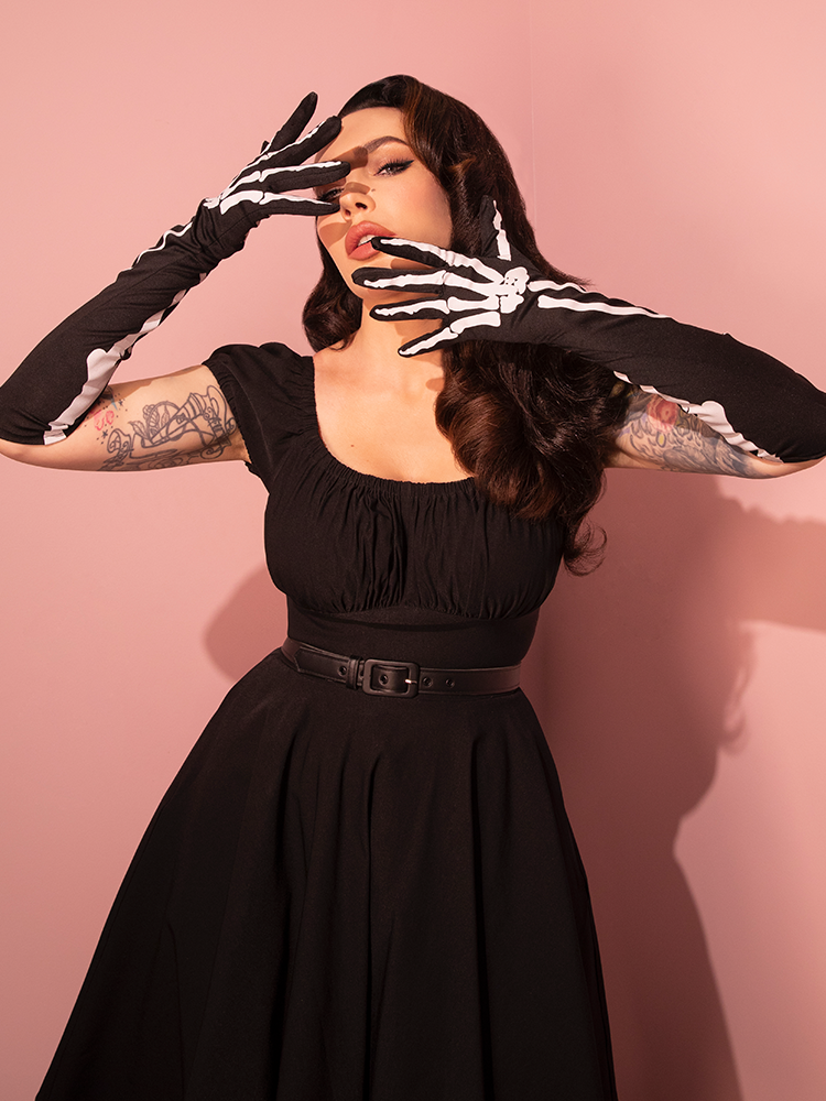 Donning the Full-length Opera Gloves in Skeleton Print from retro fashion purveyor Vixen Clothing, Micheline Pitt embraces a darkly romantic retro aesthetic.