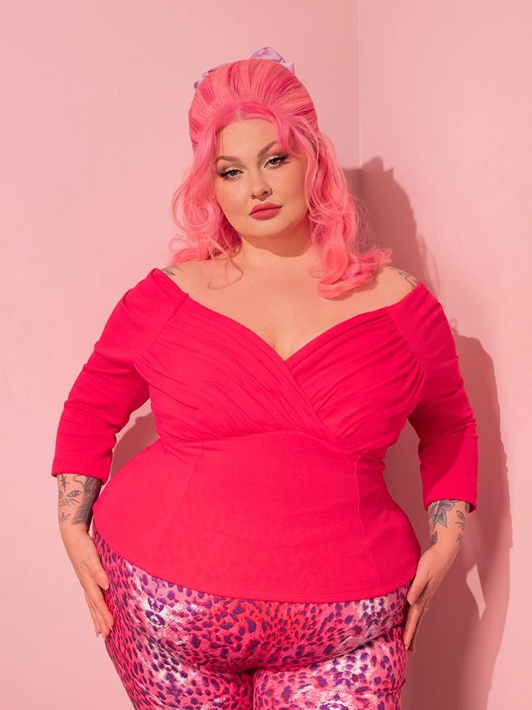 With her undeniable allure, the female model effortlessly captivates the audience as she dons the Starlet Top in Hot Pink, a striking creation from Vixen Clothing's collection of retro clothing.