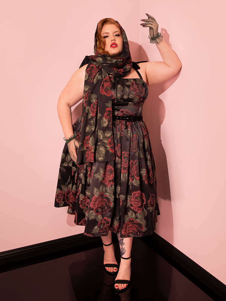 The retro model effortlessly transitions through poses, showcasing the 1950s Satin Swing Sundress and Scarf in Black Vintage Roses from Vixen Clothing with style.