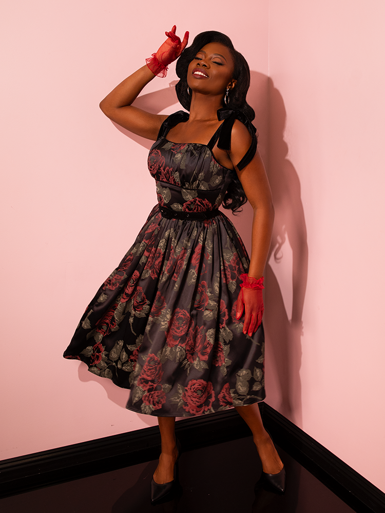 Revel in the romantic allure of the past with the 1950s Satin Swing Sundress and Scarf in Black Vintage Roses from Vixen Clothing. Watch as vintage models embody the spirit of a bygone era, showcasing this retro ensemble with style and panache.