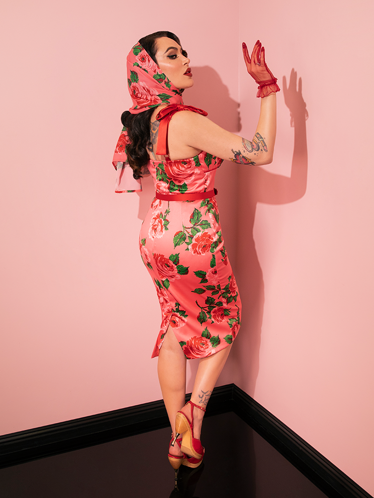 The retro clothing model captivates in the 1950s Satin Wiggle Sundress and Scarf, both adorned in Pink Vintage Roses by the renowned brand Vixen Clothing.