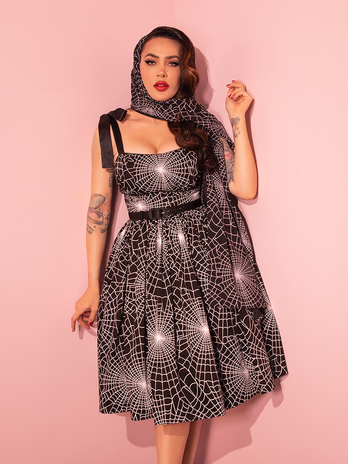 Vixen Clothing's freshly introduced 1950s Swing Sundress and Scarf, featuring a Black and White Spider Web Print, pays homage to the vintage style of yesteryears with a delightfully spooky twist.