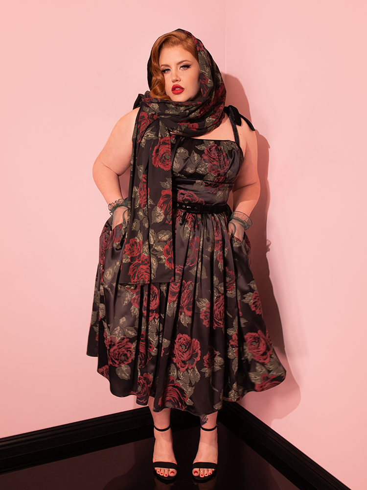 Indulge in the sophistication of the past with Vixen Clothing's 1950s Satin Swing Sundress and Scarf in Black Vintage Roses. Watch as stunning vintage models bring this retro beauty to life on the runway.