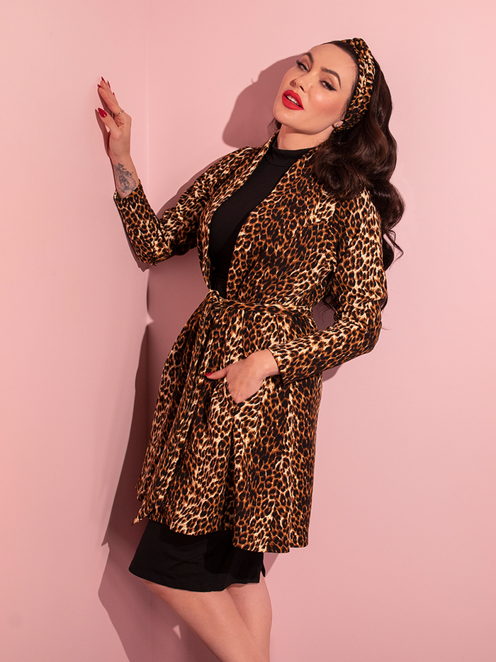 Micheline Pitt turned to the side while tucking a hand into the pocket on the Vintage Leopard Cardigan Coat from retro clothing brand Vixen Clothing.