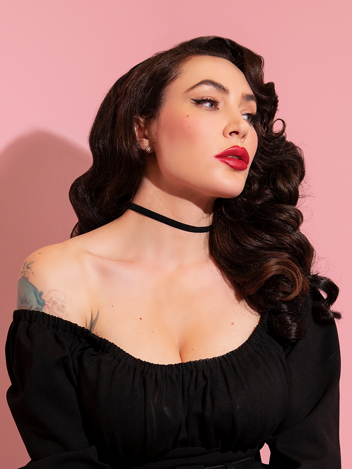 Micheline Pitt, wearing a low-cut long sleeve black top with the Vintage Style Black Velvet Choker as an accent piece. 