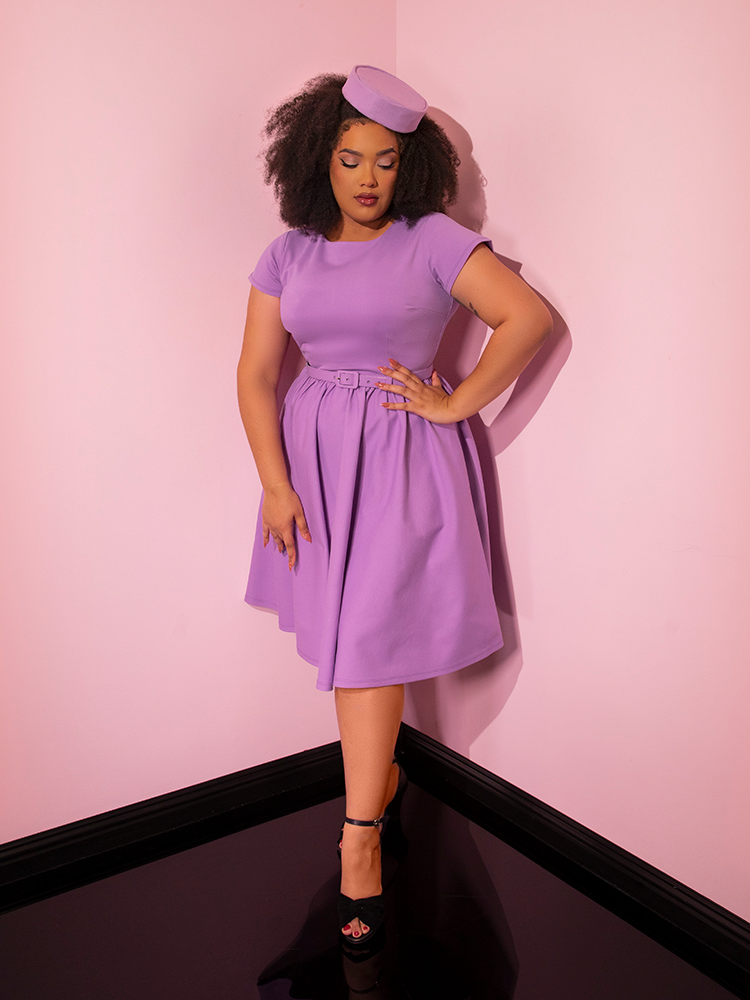 Model posing with her hand on her hip while wearing the Avon Swing Dress in Lilac.