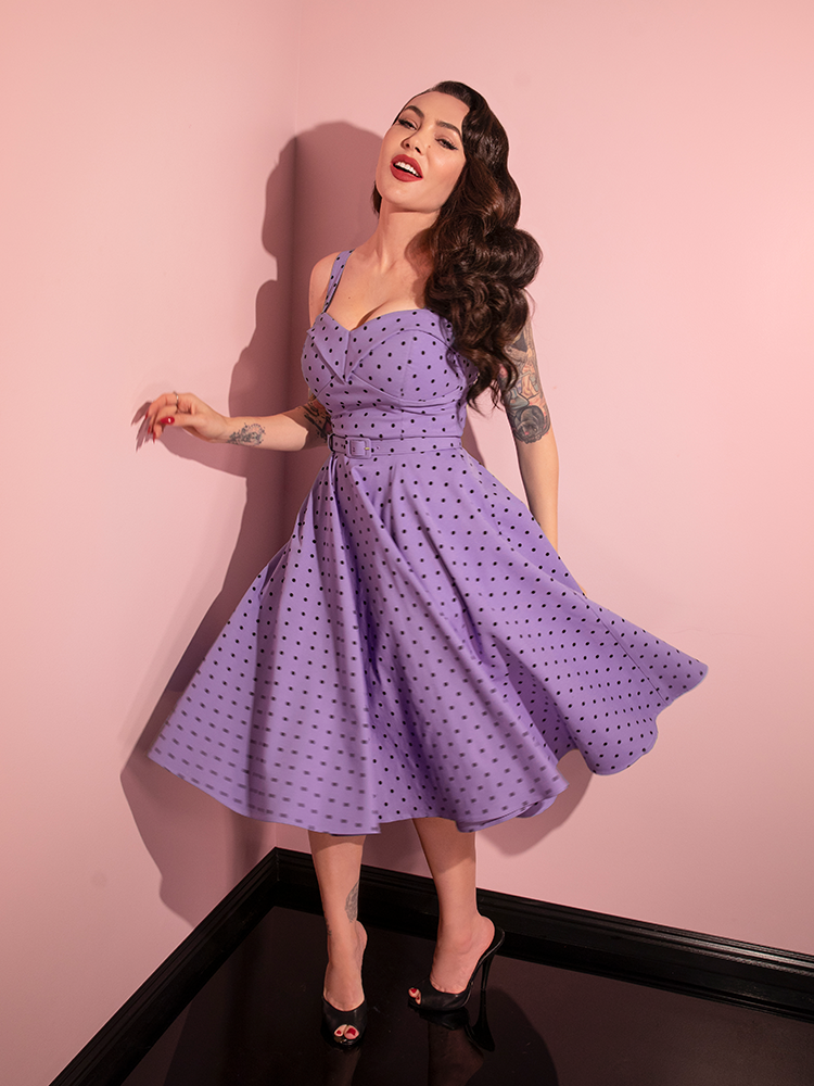 The Maneater Swing Dress in Sunset Purple Polka Dot becomes a statement piece as Micheline Pitt playfully showcases its retro allure for Vixen Clothing.