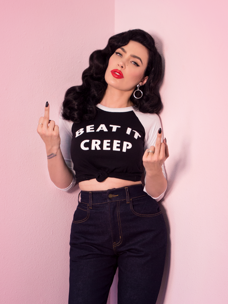 With both middle fingers up, Micheline Pitt models the Beat It Creep raglan t-shirt by Vixen Clothing.