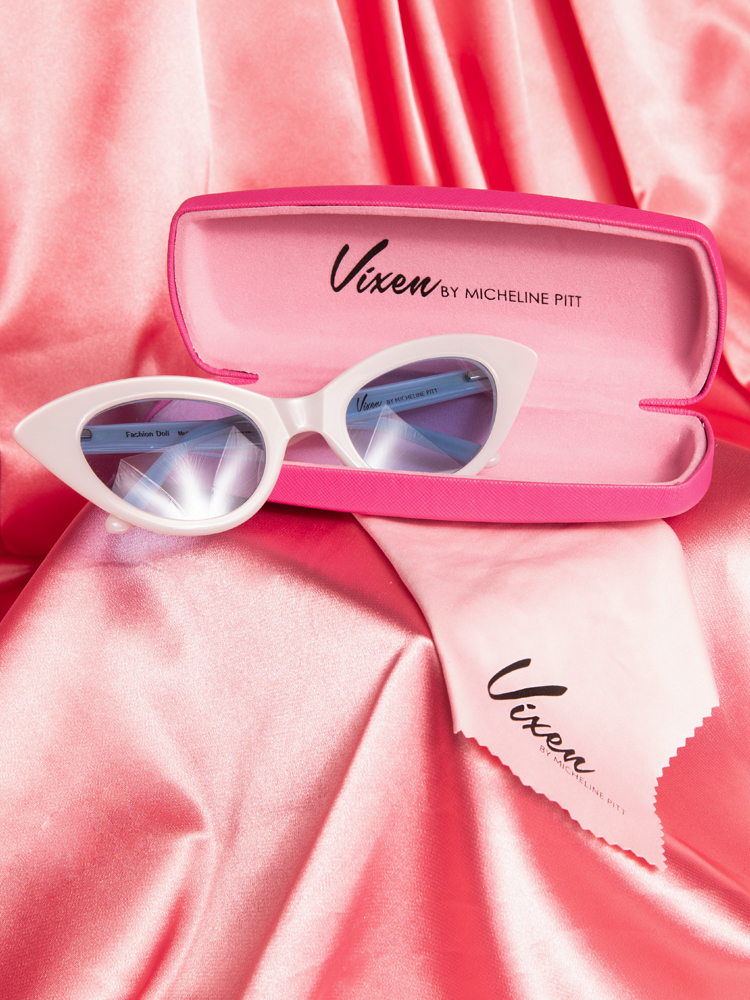 Stylized shot of the Fashion Doll Cat Eye Sunglasses in white placed on a pink satin background.
