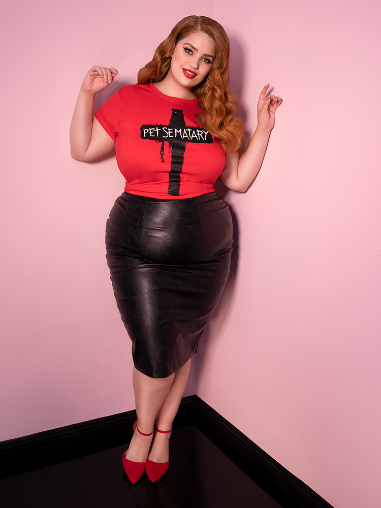 Model Bree poses in the Bad Girl Pencil Skirt in Vegan Leather along with her Pet Sematary cross shirt - all items available from vintage inspired clothing retailer Vixen Clothing.