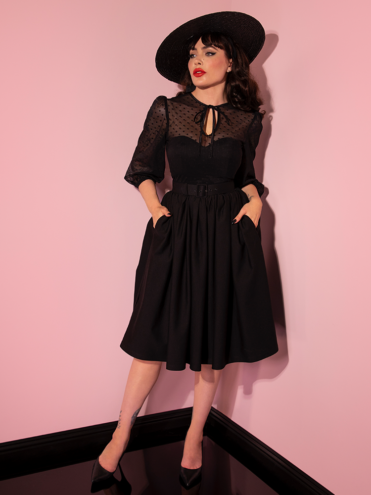 With her hands tucked into the pockets of her Frenchie Swing Dress in Black, Micheline Pitt looks like a retro queen.