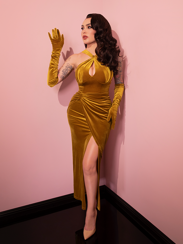 Micheline is looking to the side in a pink room while wearing the Golden Era gown and glove set.