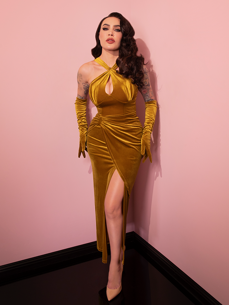 Micheline is in a pink room with her hands against her hips while wearing the Golden Era gown and glove set.