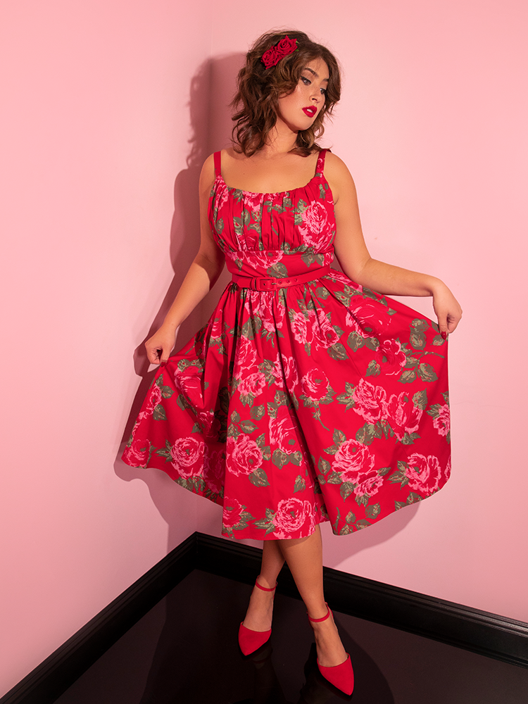 Francesca strikes a slight curtsy pose while in the Ingenue Swing Dress in Vintage Red Rose Print.
