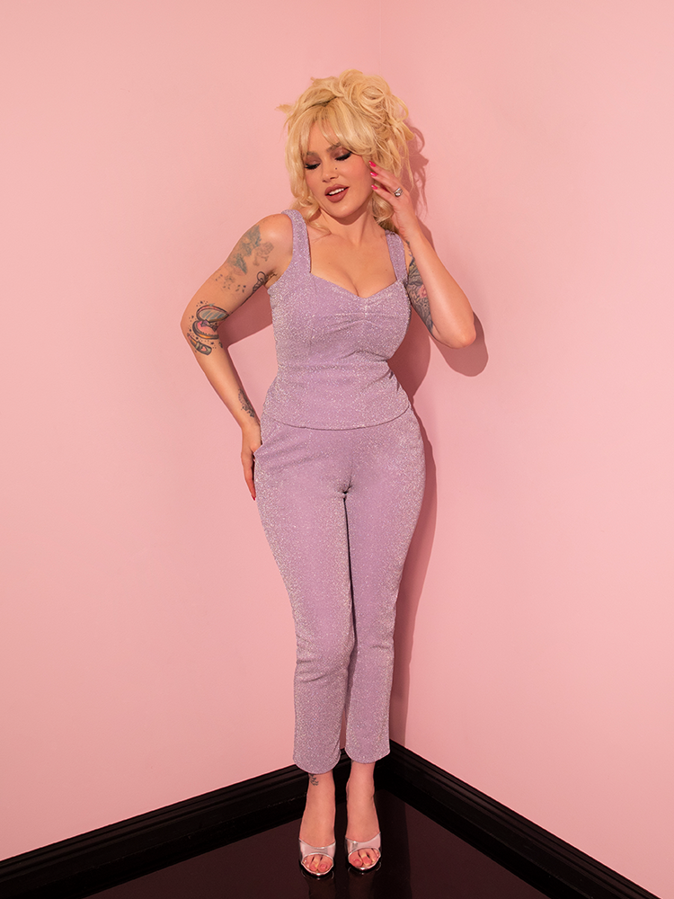 Radiating retro glamour, the female model effortlessly showcases the Lilac Lurex Cigarette Pants from Vixen Clothing, leaving a lasting impression.