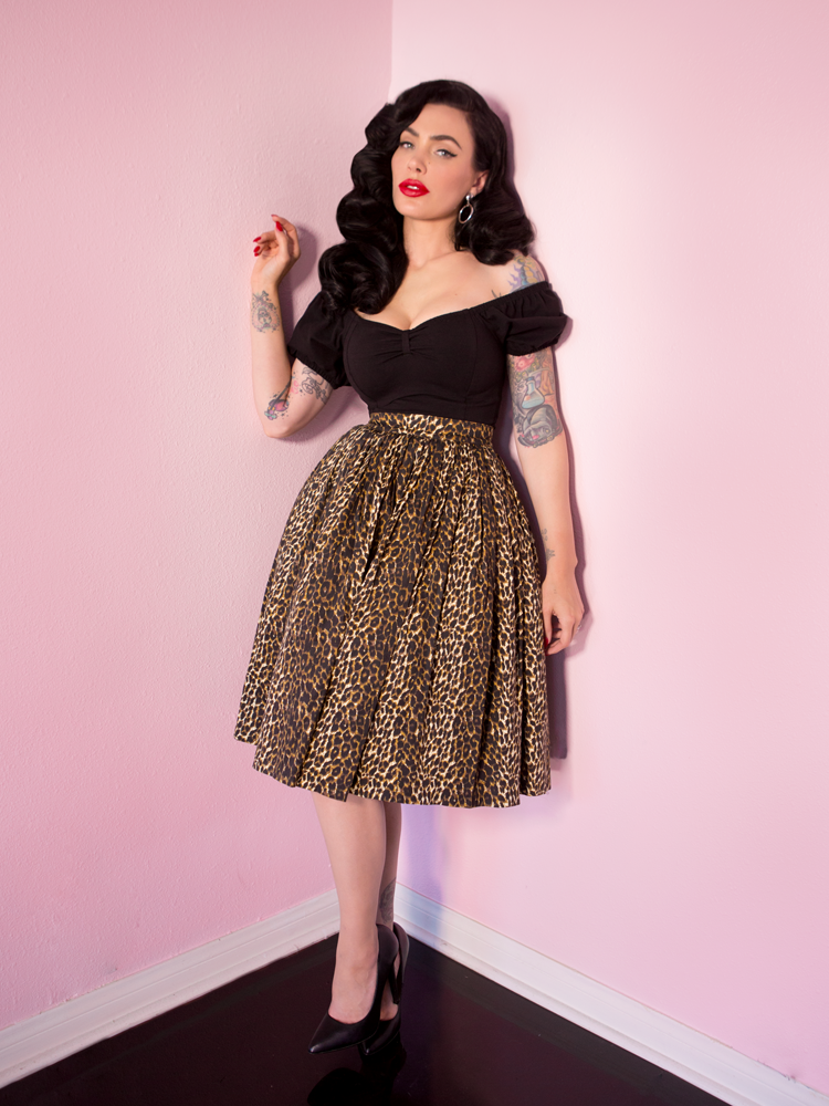 Micheline Pitt modeling the Vixen Swing Skirt in Wild Leopard Print along with a black retro top hanging off of her shoulder.