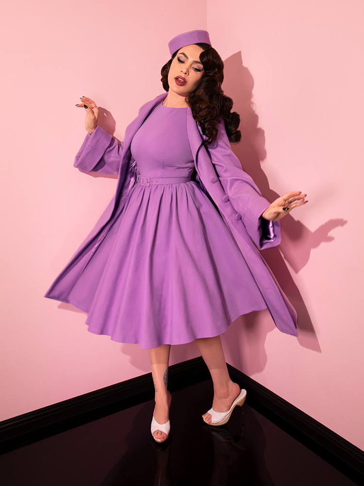 Micheline Pitt caught dancing in the Avon Swing Dress in Lilac while also wearing matching coat and hat.