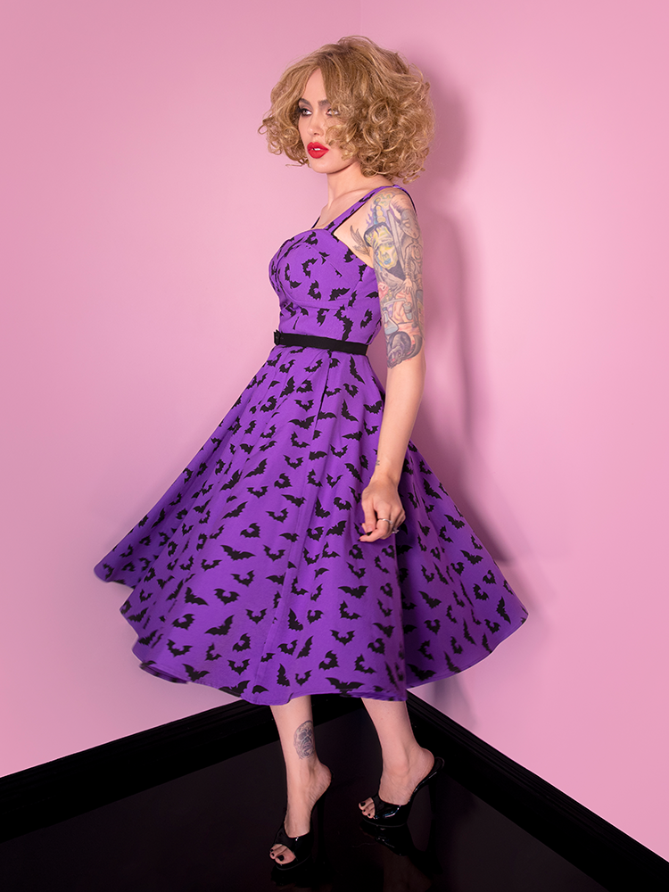 Micheline Pitt captured mid-spin in a purple swing dress featuring a bat print.