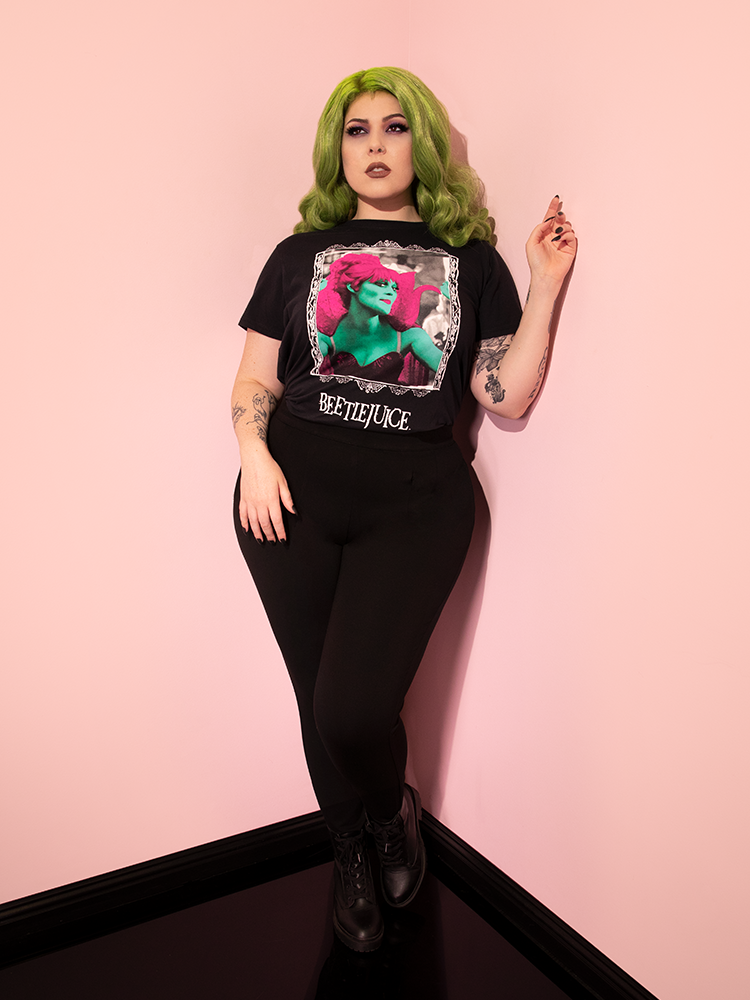 Full length shot of green-haired model wearing the Miss Argentina Tee with black pants and black boots.