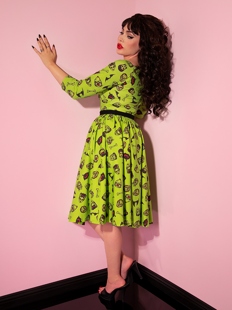Micheline Pitt turned away from the camera to show off the back of the Wicked Swing Dress in Vintage Monster Mash Print.