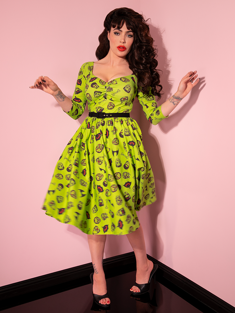 Micheline Pitt posing in an electric green retro swing dress from Vixen Clothing.