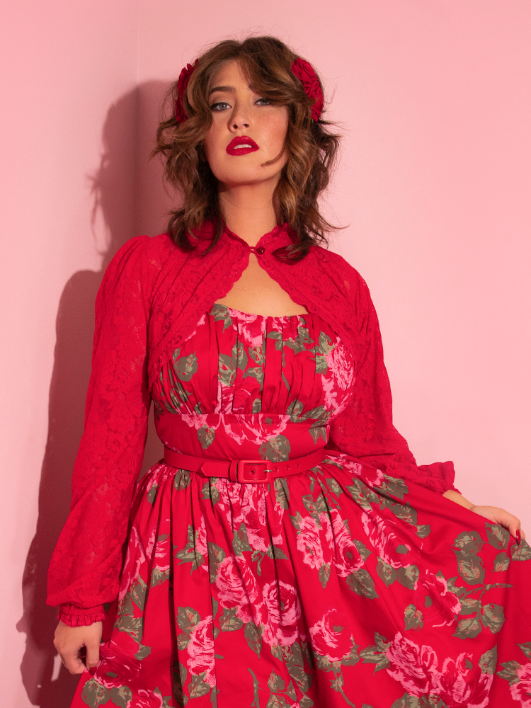 Francesa tugs out on the side of the retro inspired red rose dress she's wearing while also wearing the Vixen Vintage Lace Bolero in Classic Red. 