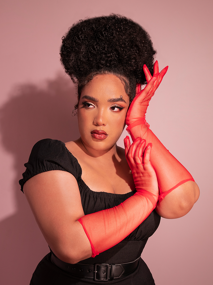 Model Ashleeta posing in the Vintage Inspired Sheer Gloves in Red with a retro style black top tucked into black pants.