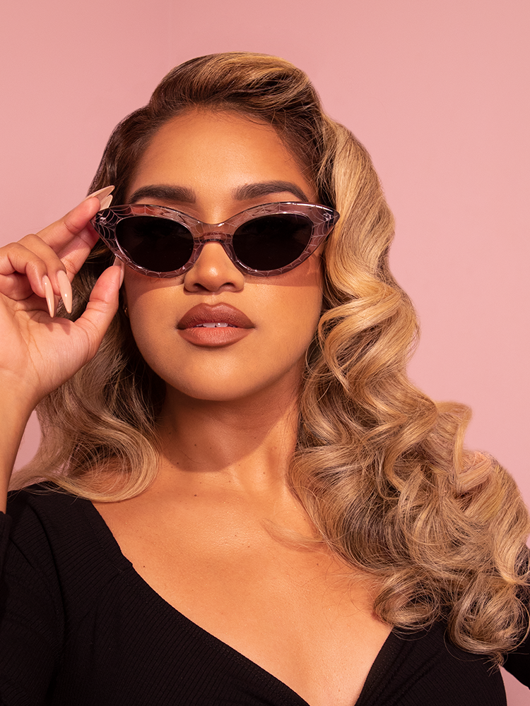 The Fashion Doll Cat Eye Sunglasses in Spider Web being worn by blonde, tan model from Vixen Clothing.