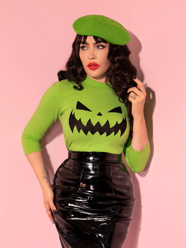 Micheline Pitt looks off camera while posing in the Pumpkin King 3/4 Sleeve Top in Slime Green.