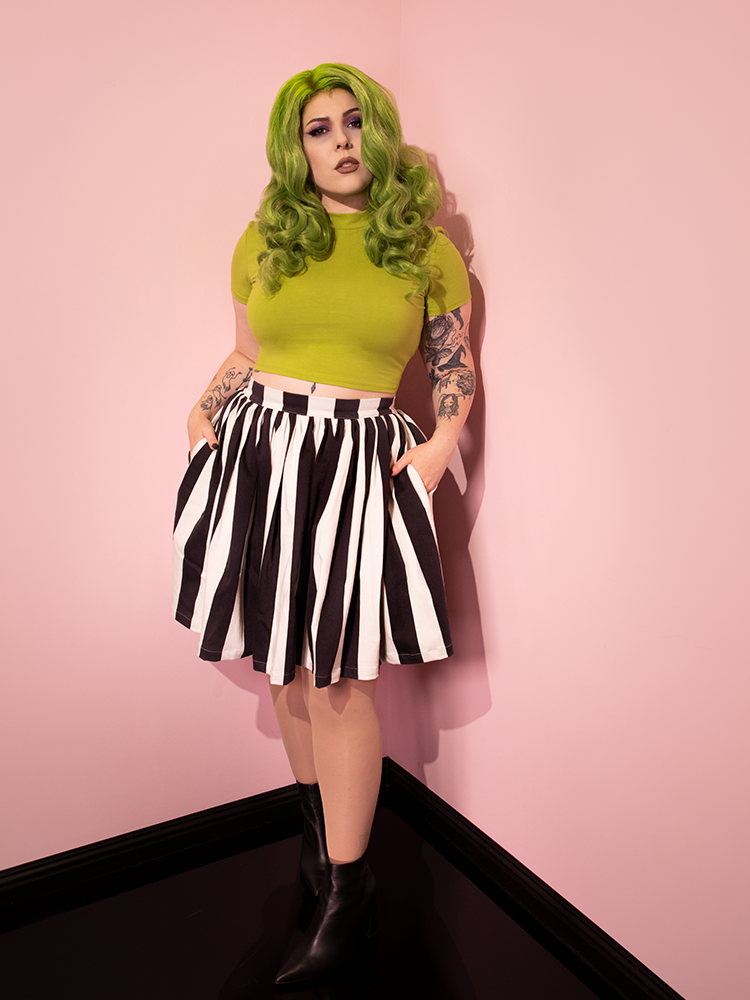 Full length image of a green haired female model wearing a retro style outfit including the Ghost Skater Skirt in Black & White Stripes.