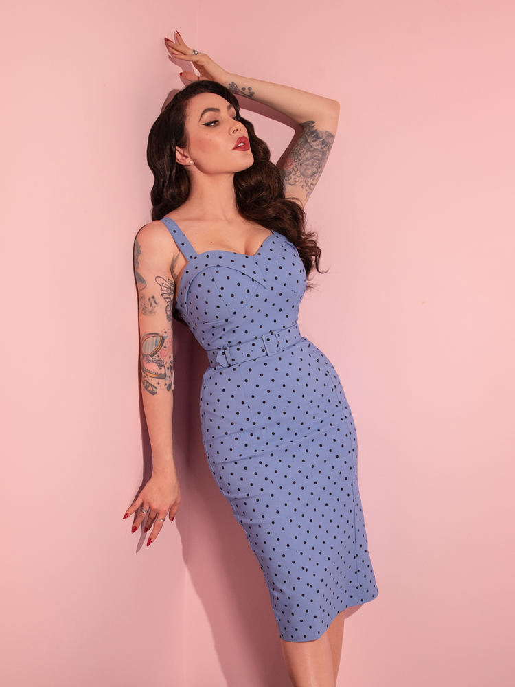 Micheline Pitt gazes off in the distance while wearing the Maneater Wiggle Dress in Sunset Blue Polka Dot.