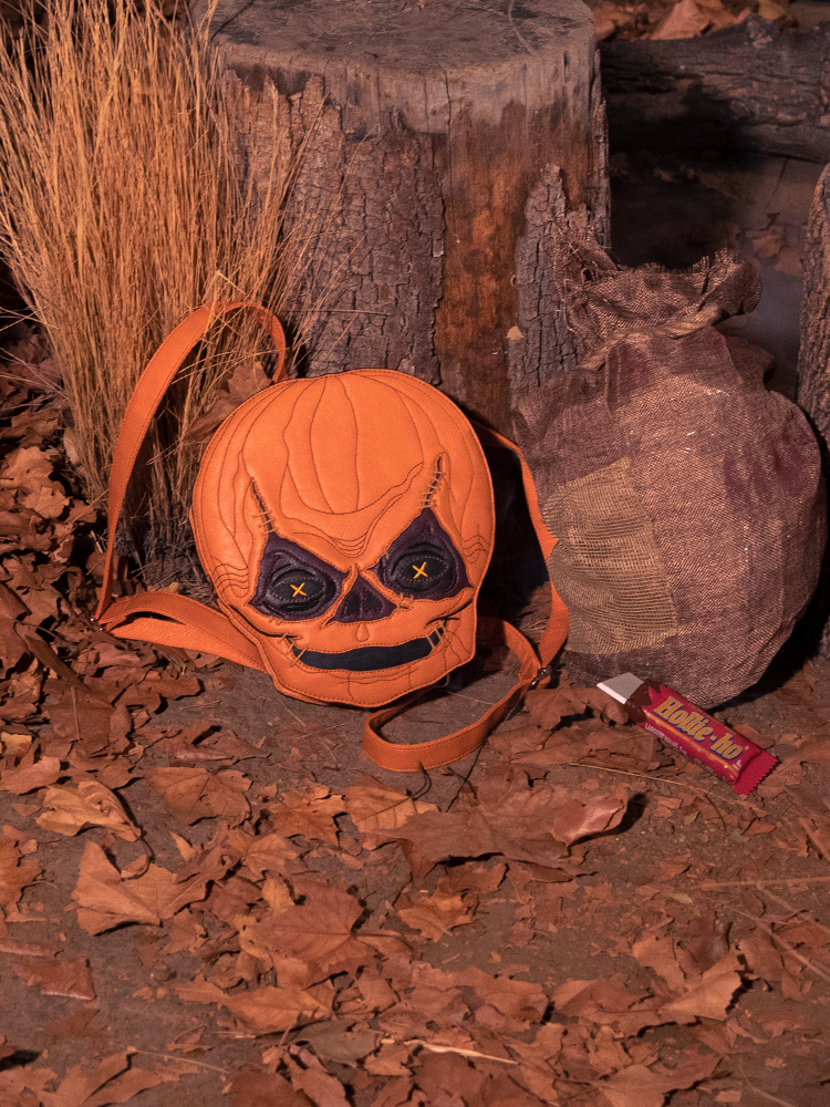 Retro clothing brand, Vixen Clothing, releases the TRICK R TREAT™ Sam Backpack sitting in front of a dead tree and leaves.