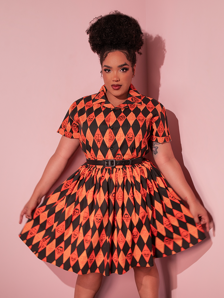 Model pulls out the sides of the skirt to show off the festively spooky print that matches the TRICK R TREAT™ Button Up Shirt in Halloween Harlequin Print.