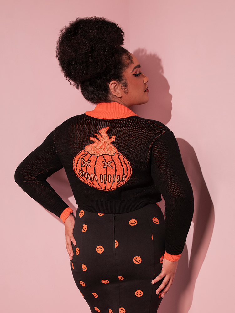 The back of the TRICK R TREAT™ Flaming Pumpkin Cropped Knit Jacket worn by Vixen Clothing model Ashleeta.