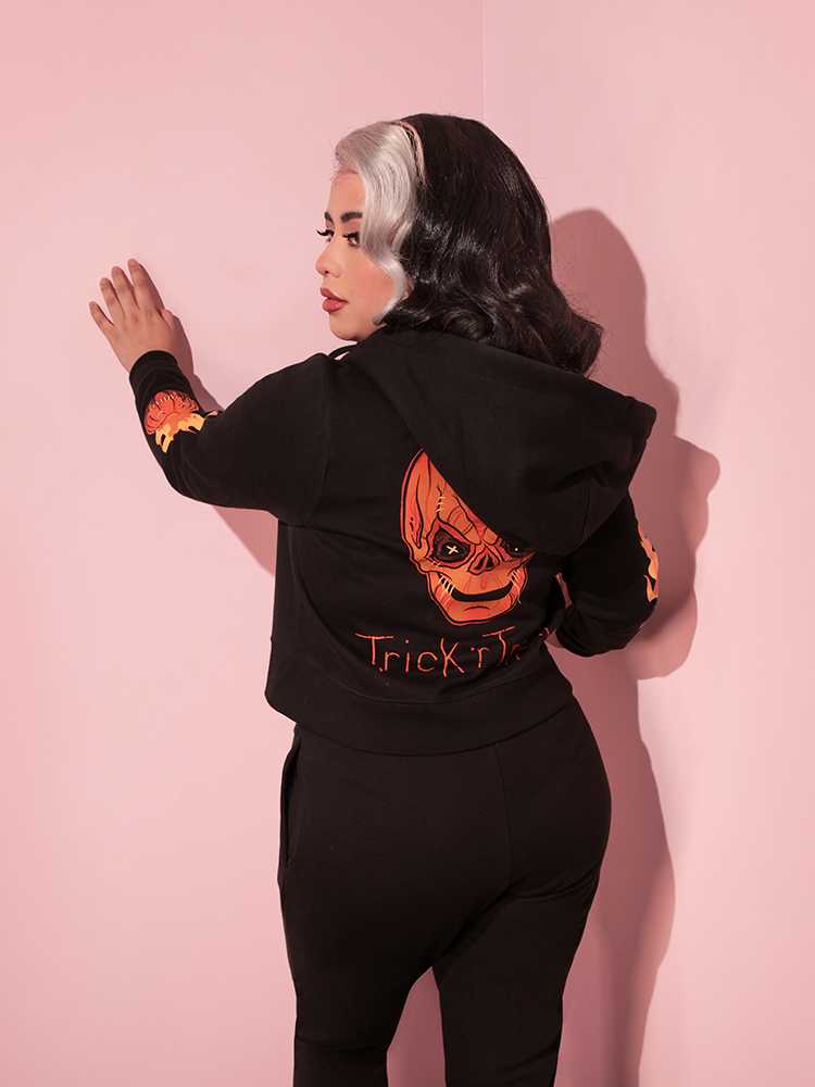 Model facing away from the camera shows off the back of the TRICK R TREAT™ Sam Cropped Hoodie feauring original creature art directly from the iconic horror film, Trick r Treat.