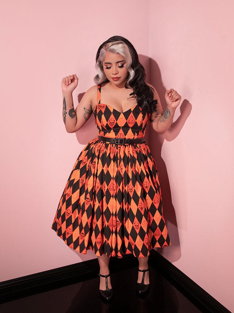 Model dancing around in the TRICK R TREAT™ Sweetheart Swing Dress in Halloween Harlequin Print with black shoes