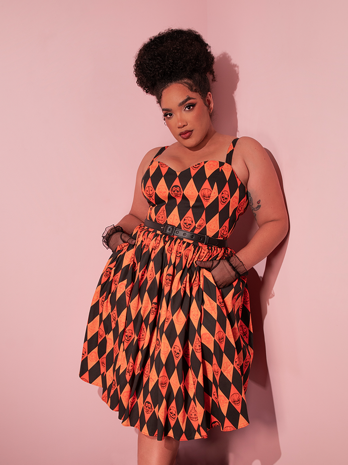 Model tucking her hands into the deep side pockets of the TRICK R TREAT™ Sweetheart Swing Dress in Halloween Harlequin Print.