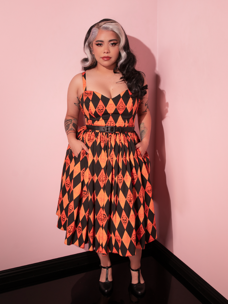 Model tucking her hands into the pockets on the TRICK R TREAT™ Sweetheart Swing Dress in Halloween Harlequin Print.